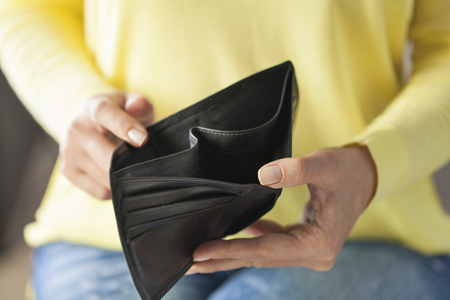 Woman looking at his empty leather wallet in homeの写真素材