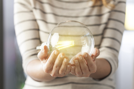Closeup hand holding light bulb. New ideas and creativity concept.の写真素材