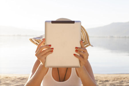Young woman using tablet computer on the beachの写真素材