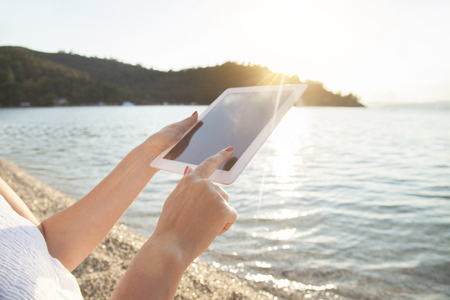 Close-up of woman using digital tablet on the beachの写真素材