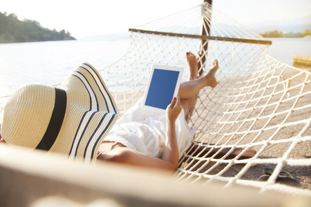 Woman using tablet pc on hammockの写真素材