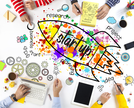 Creative team sitting at table and pointing finger to rocket icon in officeの写真素材