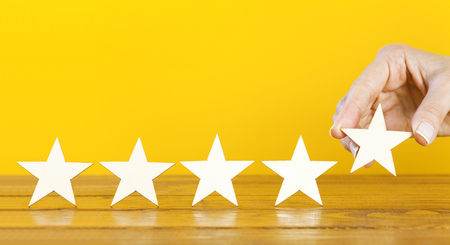 A female hand puts the fifth wooden star on a tableの写真素材