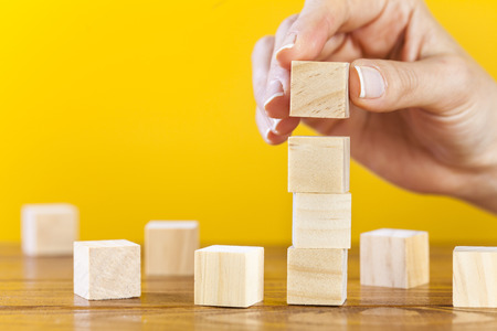 Woman hand arranging blank wooden cubes, business concept, mock up, templateの写真素材