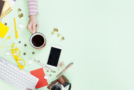 Woman holding a cup of coffee on table top view. Female blogger working deskの写真素材