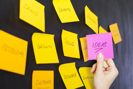 Hand with adhesive paper note and sticky on the wallの写真素材