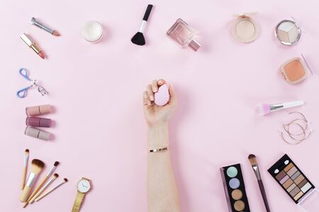 Makeup products and female hand holding makeup sponge on pink backgroundの写真素材