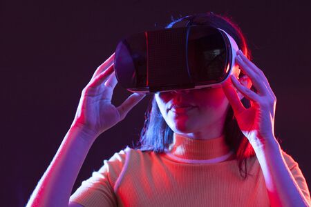 Young woman wearing virtual reality device over grey backgroundの写真素材