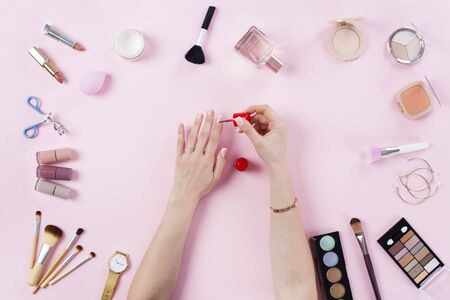 Female hands doing nail polish on pink tableの写真素材