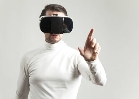Young man wearing virtual reality device over white backgroundの写真素材