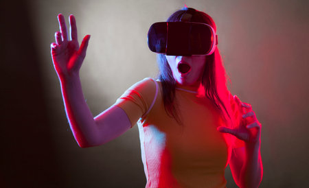 Young woman wearing virtual reality device over dark backgroundの写真素材