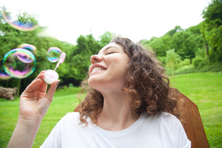 Young woman having fun and blowing bubbles outdoors 