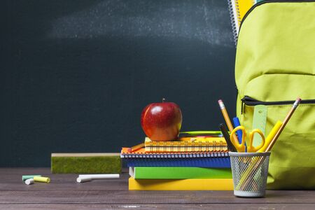 Stack of books, stationery and education supplies on wooden desk. Back to school concept.の写真素材