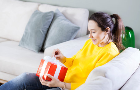 Young woman with gift for Valentine's Day or her birthday at home