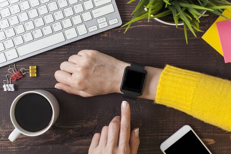 Businesswoman using smartwatch while working at office, woman touching on smartwatch screen.の写真素材