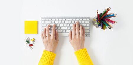 Top view on female elegant hands on a computer keyboard. Isolated white background. Simple design, large copy space for your designsの写真素材