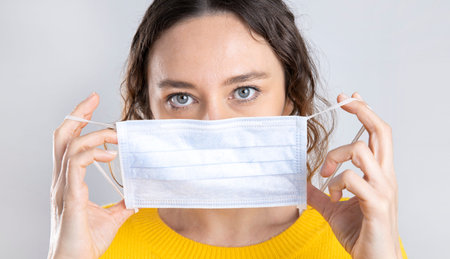 Young woman holding a yellow blank placard against a green background