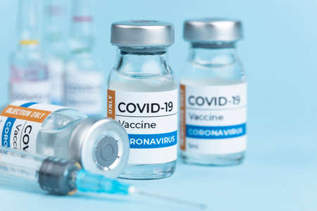 Coronavirus Covid-19 Vaccine vial glass bottles and syringe on blue backgroundの写真素材