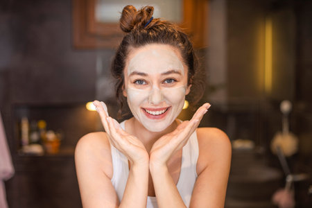 Young woman applying face mask at home