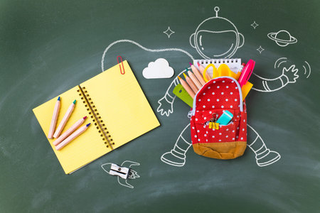 Back to school concept with miniature bag backpack, school supplies and astronaut sketch over...