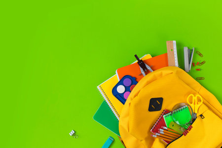 Backpack with school supplies spilling out green ground. Back to School concept.