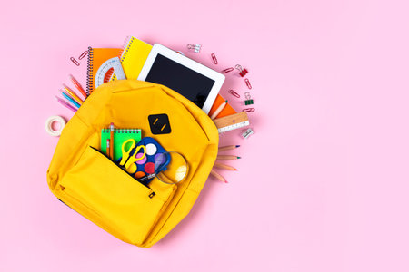 Backpack with school supplies spilling out pink ground. Back to School concept.