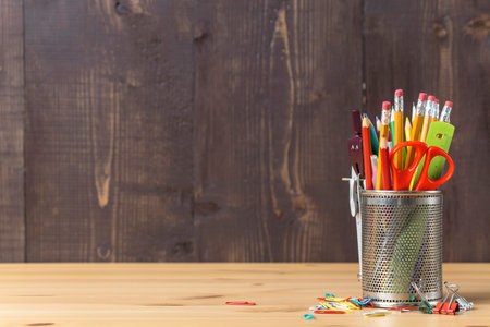 Pencils and school supplies in pencil case on wooden background