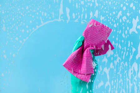 Female hand in green gloves cleaning window pane with rag. Cleaning conceptの写真素材