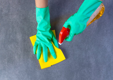 Female hands with rubber gloves cleaning floor with detergent and clothの写真素材
