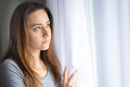 Pensive young woman looking through a window