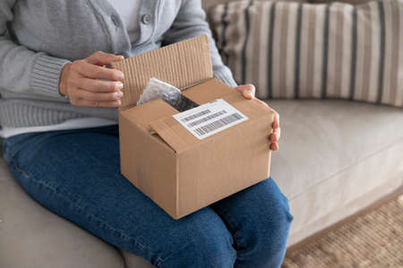 Woman opening personal online shopping parcel. Online shopping at homeの写真素材