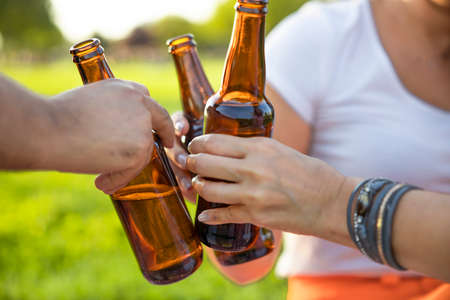 The hands holding bottles with beer and making cheersの写真素材
