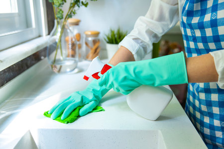 Unrecognizable woman cleaning kitchen counter with rag and spray cleanerの写真素材