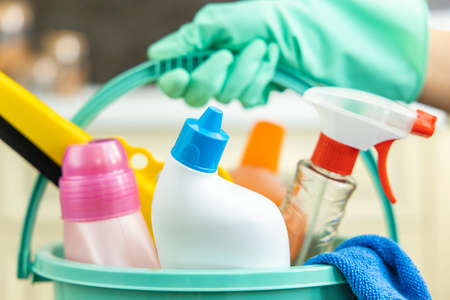 Housewife with apron holding a green bucket with cleaning suppliesの写真素材