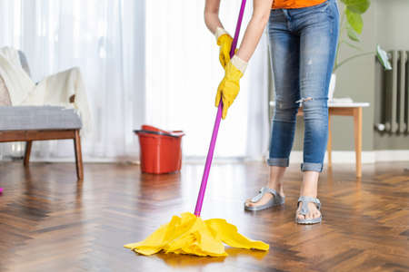 Young housewife cleaning wooden parquet using microfiber mop pad. Routine house chores conceptの写真素材