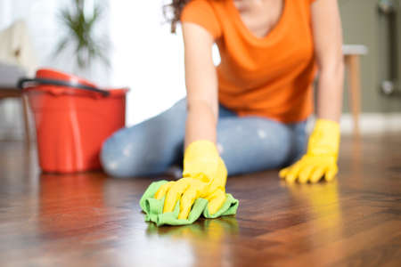 Young housewife with gloves cleaning the floor. Routine house chores conceptの写真素材