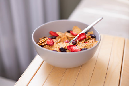 Tasty corn flakes with strawberries in bowl on wooden tableの写真素材