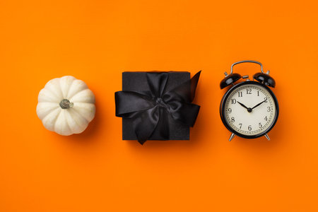 Black gift box, clock and pumpkin, Thanksgiving and black friday sales concept on orange background