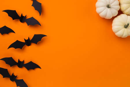 Happy halloween holiday concept. Halloween decorations, pumpkins and bats on orange background. Halloween party greeting card mockup with copy space. Flat lay, top view, overhead.の写真素材