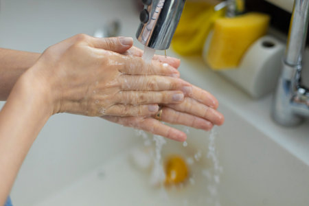 Cropped shot of an unrecognizable woman washing his hands in the kitchen sink at home