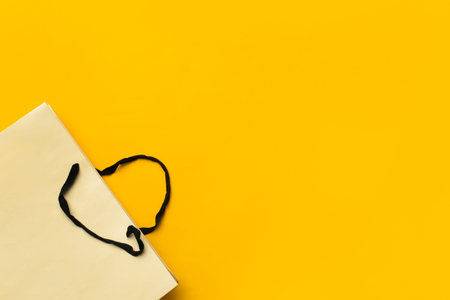 Empty paper shopping bag on yellow background. Black friday concept. Top view, flat lay