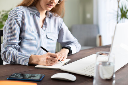 Young woman working with a laptop. Female freelancer connecting to internet at home. Blogger writing...
