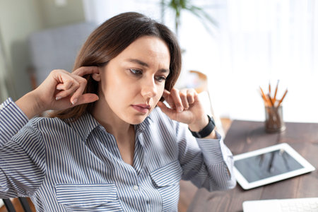 Young woman suffering with a earache at home office