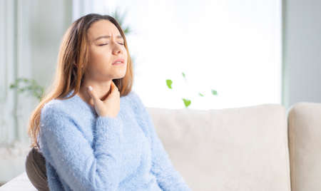 Young woman touching painful neck, sore throat for flu, cold and infectionの写真素材
