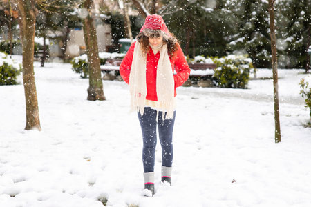 Young woman in red coat walking in the city on a snowy winter day