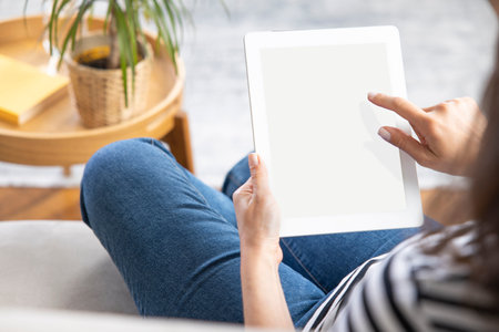 Young woman using tablet pc while sitting at home and communicate with friends in social networks,...