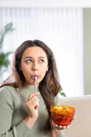 Young woman eating breakfast cereals of bowl at home