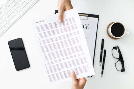 Businessman and businesswoman are exchanging contract or document. Office table top viewの写真素材