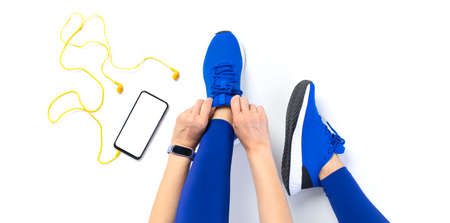 Young woman tying shoelace before workout, getting ready for joggingの写真素材