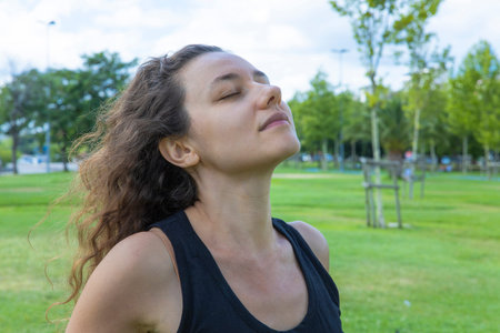 Young woman relaxing, feeling alive, breathing fresh air, calm and dreaming with closed eyes, in...